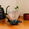 Dripper de vidrio con base sobre una mesa de madera