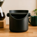 Knock box para borra de café sobre una mesa de madera