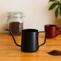 Tetera cuello de ganso negra sobre una mesa de madera